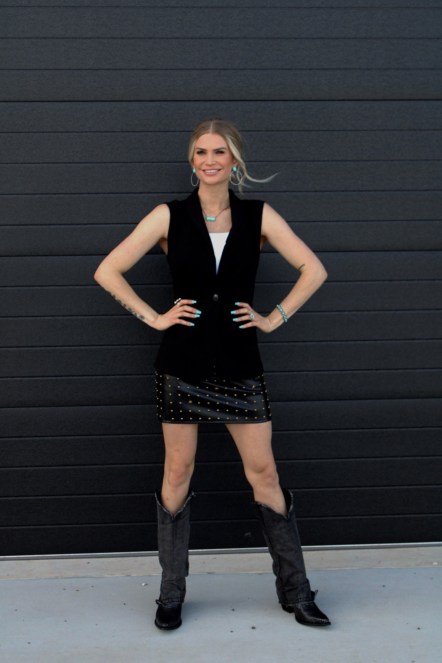 Woman in a black outfit with a black wall background