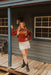 Woman standing on a wooden porch in front of a rustic building