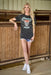 Woman wearing a 'Cowboy Rodeo' t-shirt in an indoor arena setting