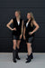 Two women in matching black outfits standing against a black background