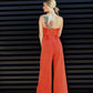 Woman wearing an orange jumpsuit against a black slatted wall.