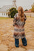 Person wearing a patterned cardigan standing on a stone path with a church in the background