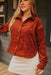 Woman wearing a rust-colored corduroy shirt and white skirt outdoors.