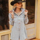 Woman wearing a denim dress and cowboy hat in front of a wooden building.