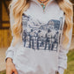 Person wearing a gray hoodie with a graphic design of cowboys and a barn.