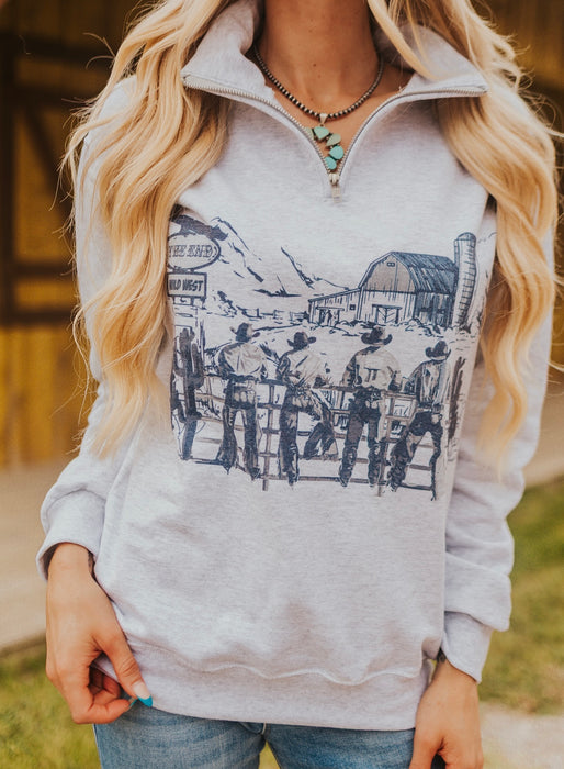 Person wearing a gray hoodie with a graphic design of cowboys and a barn.