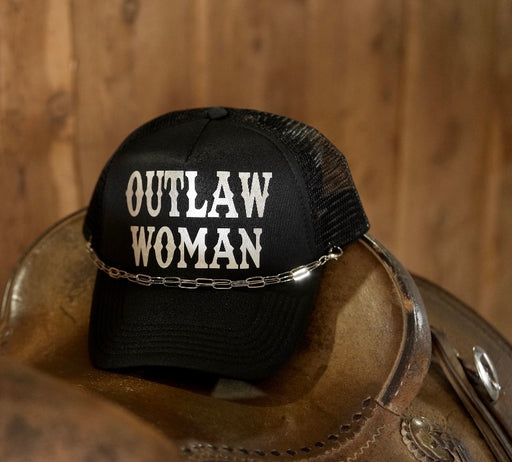 Black cap with 'Outlaw Woman' text on a wooden surface
