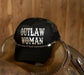 Black cap with 'Outlaw Woman' text on a wooden surface