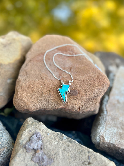 Turquoise thunderbolt necklace on a rock with a natural background