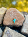 Turquoise thunderbolt necklace on a rock with a natural background
