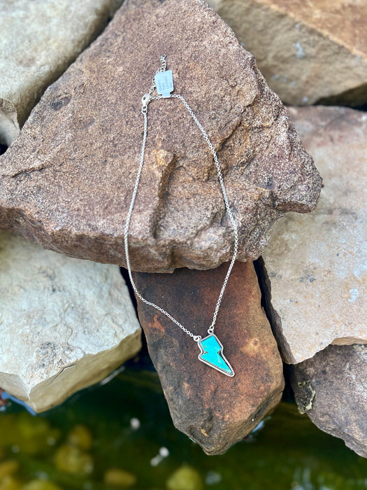 Necklace with a turquoise pendant on a stone surface