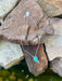 Necklace with a turquoise pendant on a stone surface