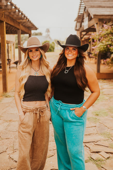 Two women wearing cowboy hats and casual outfits standing outdoors.
