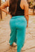 Person wearing turquoise pants and a black top on a stone path.