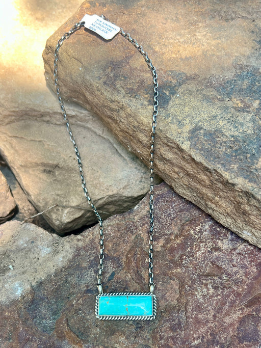 Necklace with turquoise pendant on a stone surface