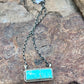 Turquoise pendant necklace on a chain on a rocky surface