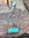 Turquoise pendant necklace on a chain on a rocky surface