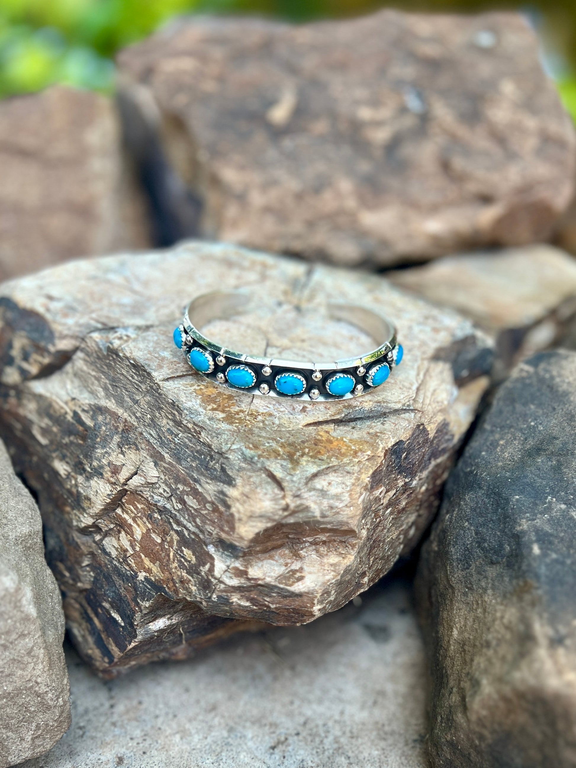 Silver bracelet with blue stones on a rock