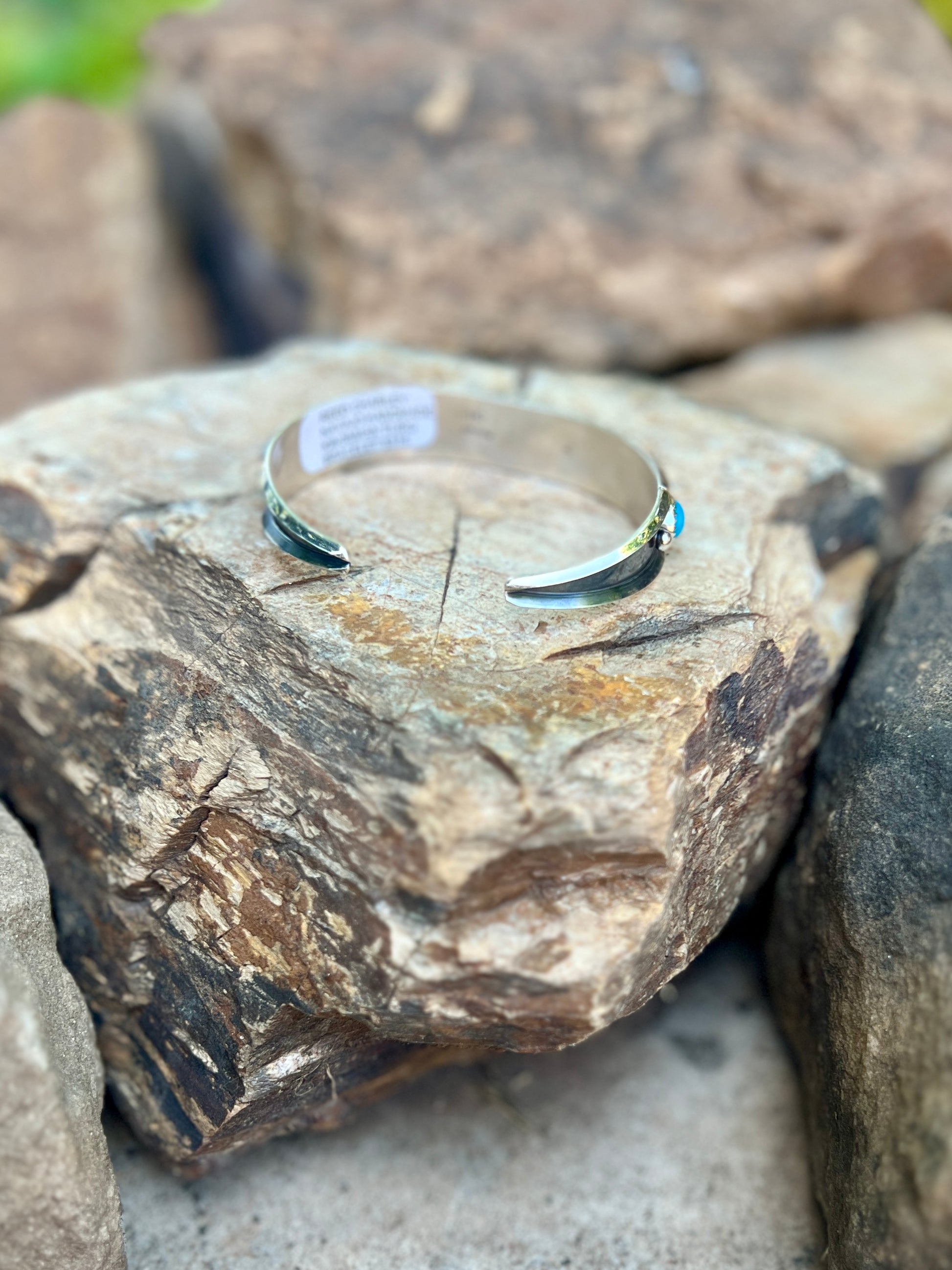 Silverbracelet with a blue stone on a rough stone surface