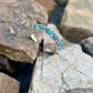 Silver bracelet with turquoise stones on a rocky surface