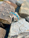 Silver bracelet with turquoise stones on a rocky surface