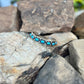 Silver bracelet with turquoise stones on a rock background