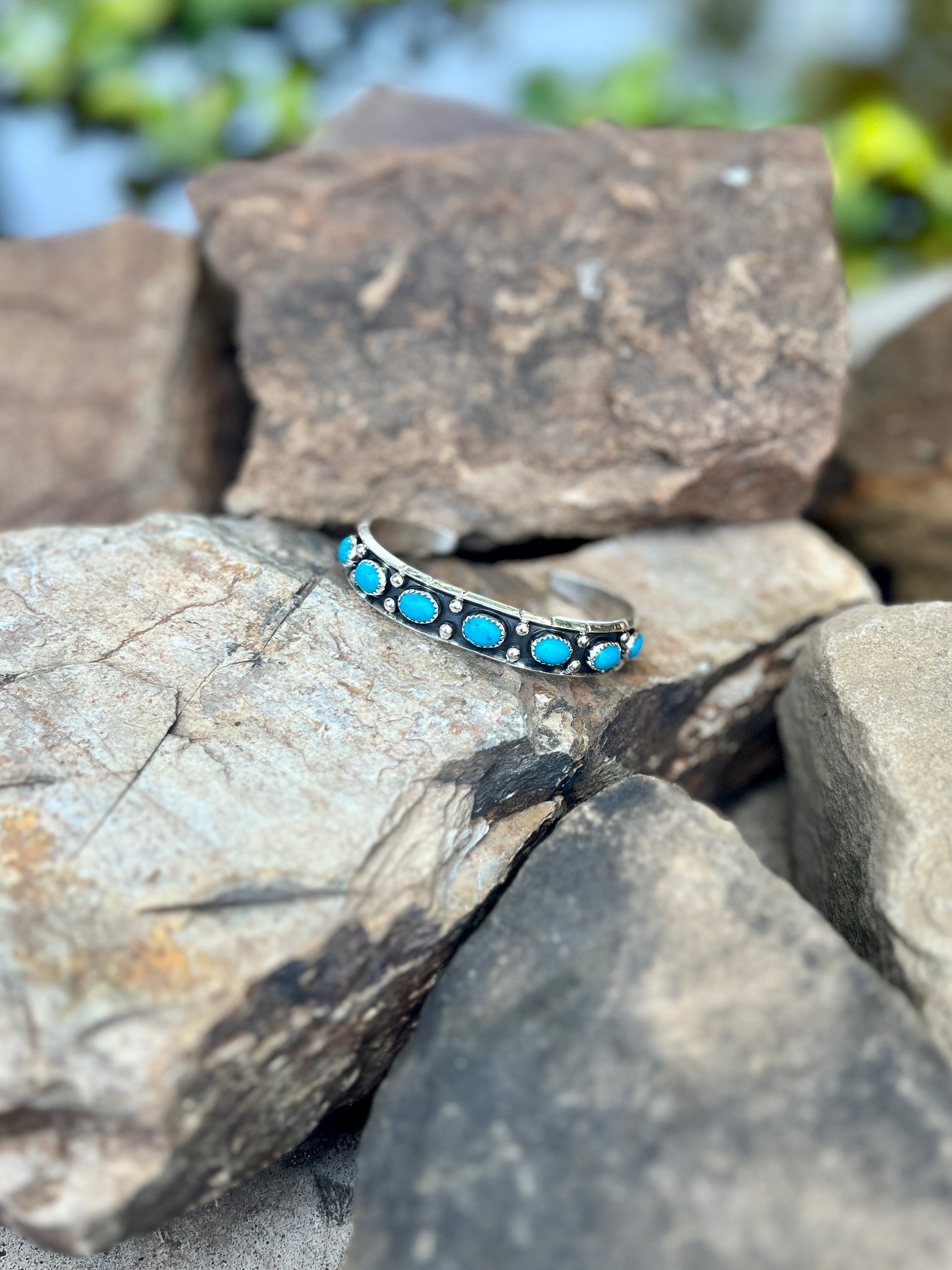 Silver bracelet with turquoise stones on a rock background