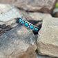 Silver bracelet with turquoise stones on a rock background