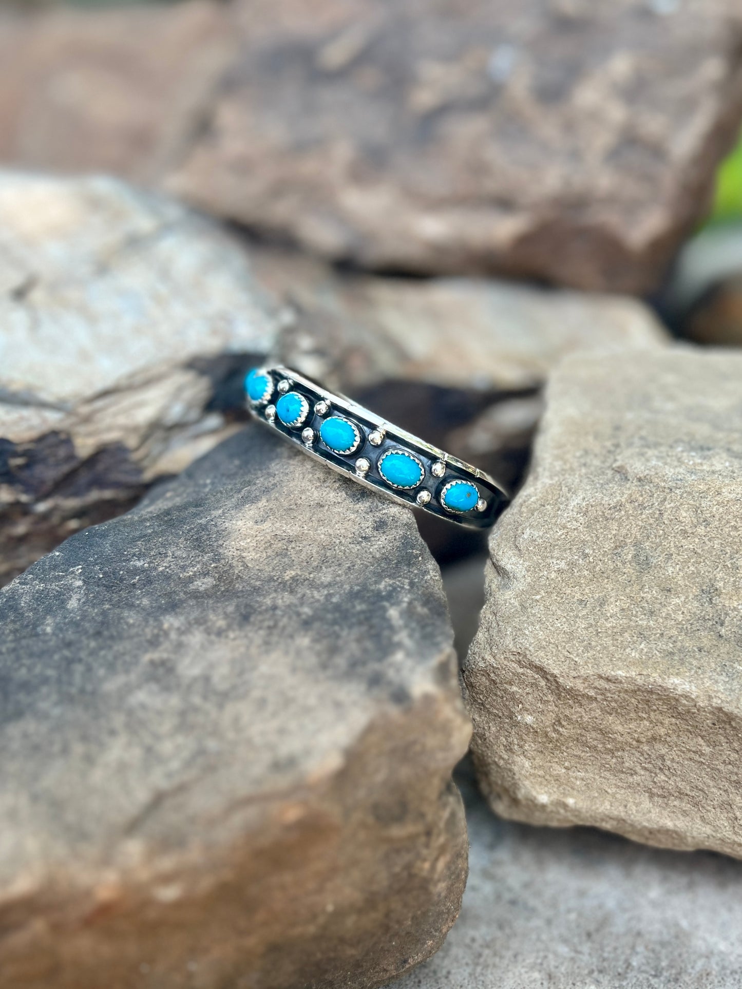 Silver ring with turquoise stones on a rock background