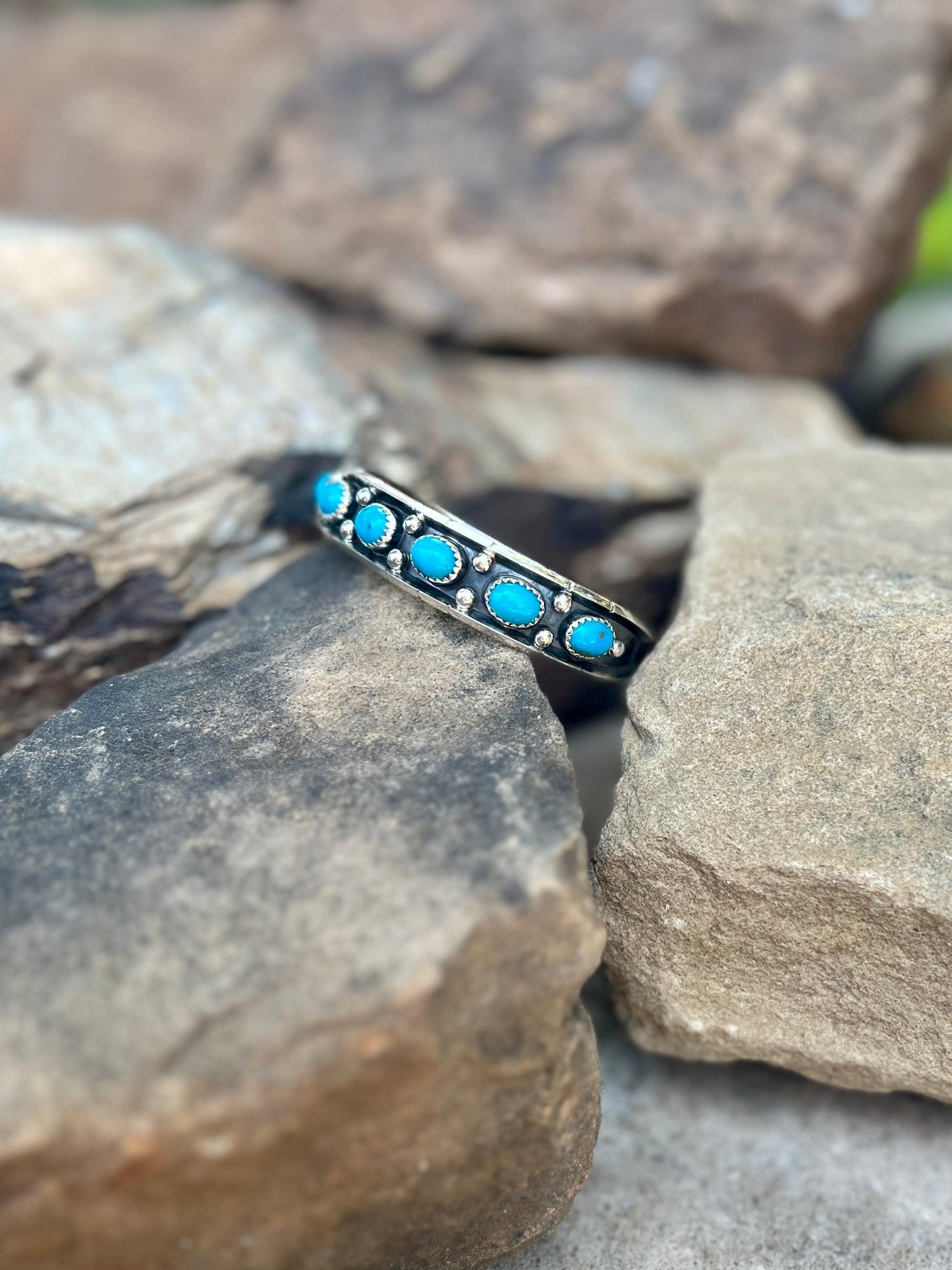 Silver ring with turquoise stones on a rock background