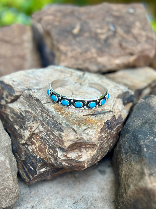 Silver bracelet with blue stones on a rock