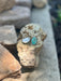 Two earrings displaying the 425 silver stamp on a rock with a natural background