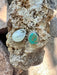 Turquoise stone and silver earring on a rock