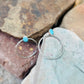 Silver hoop earrings with turquoise stones on a stone surface