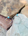 Silver hoop earrings with turquoise stones on a stone surface