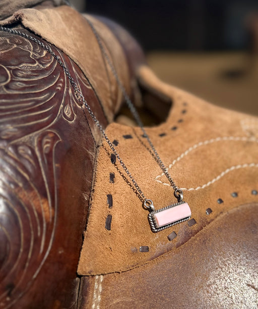 Necklace with a pink pendant on a brown leather surface