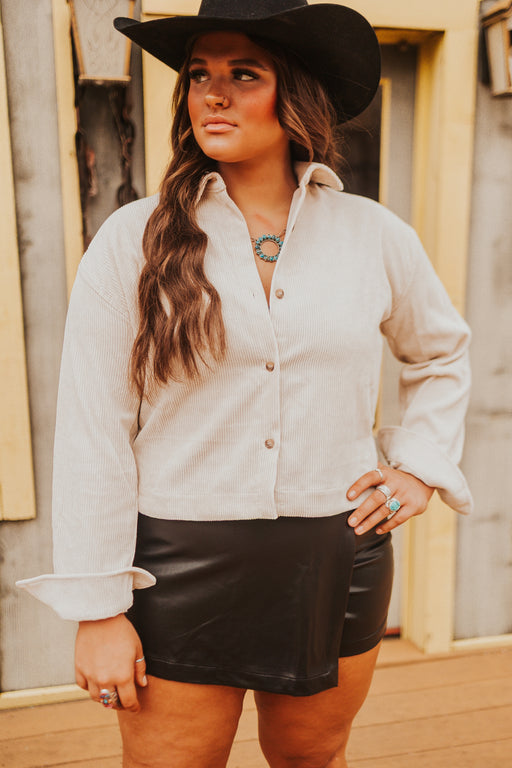 Woman wearing a white blouse, black skirt, and black hat outdoors.