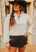 Woman wearing a white blouse, black skirt, and black hat outdoors.