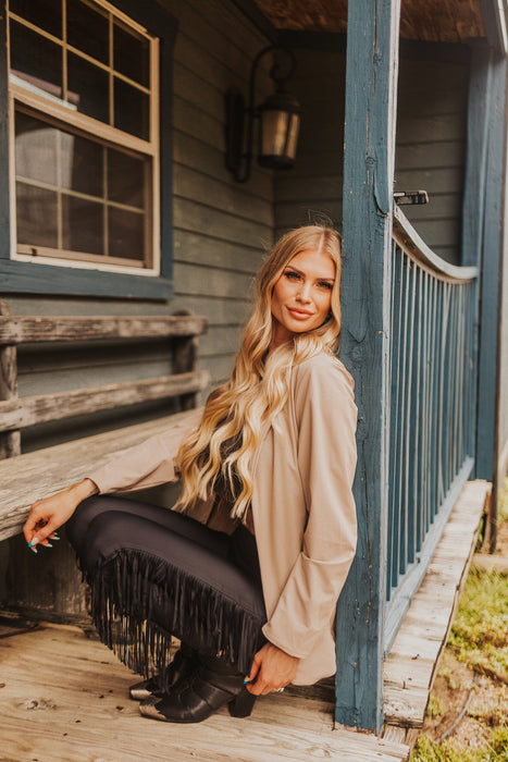 Woman sitting on a wooden porch with a rustic cabin background