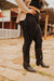 Person wearing black leggings and knee-high boots on a stone path with wooden structures in the background.