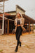 Woman in a stylish outfit standing in front of a rustic building.