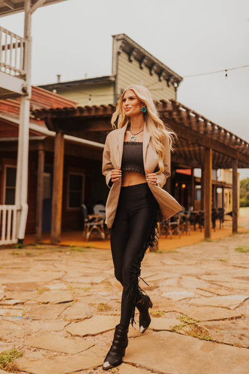 Woman in a stylish outfit standing in front of a rustic building.
