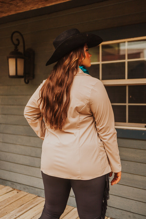 Person wearing a beige jacket and black hat standing on a wooden deck.