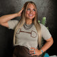 Woman wearing a shirt with a horse bit design in front of a dark background