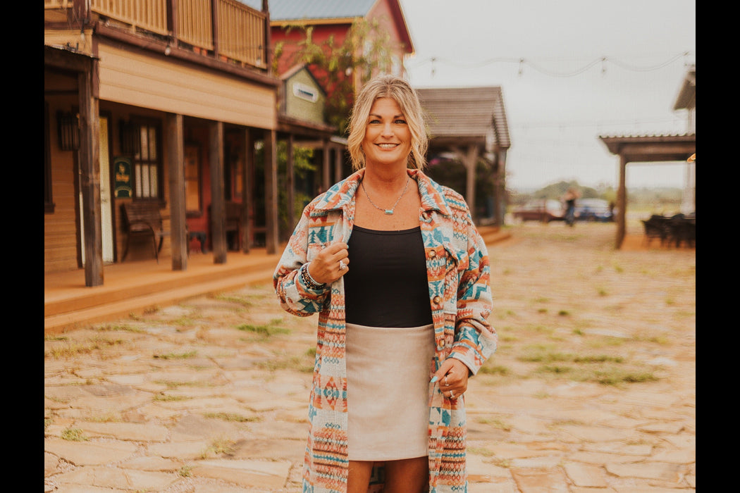 Woman standing on a stone path in front of wooden buildings