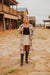 Woman standing on a stone path in front of wooden buildings