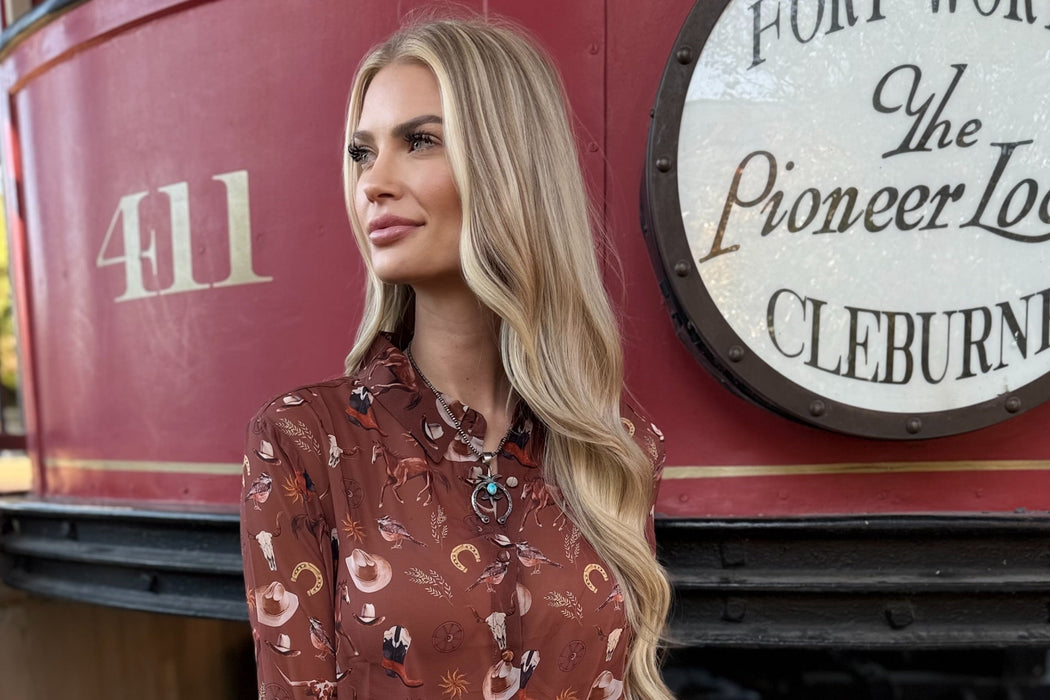 Woman in a patterned shirt and jeans standing in front of a red trolley with 'Fort Worth' and 'Cleburne' text.